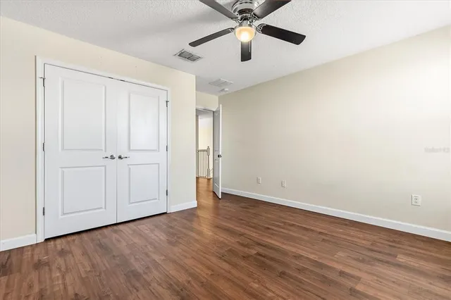 an empty room with wooden floor closet and windows