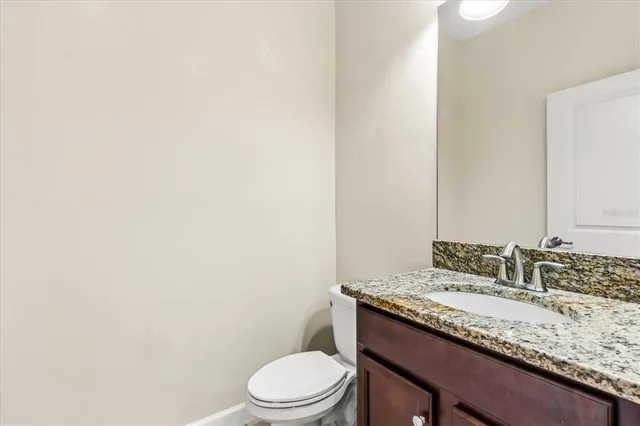 a bathroom with a granite countertop sink a toilet and mirror