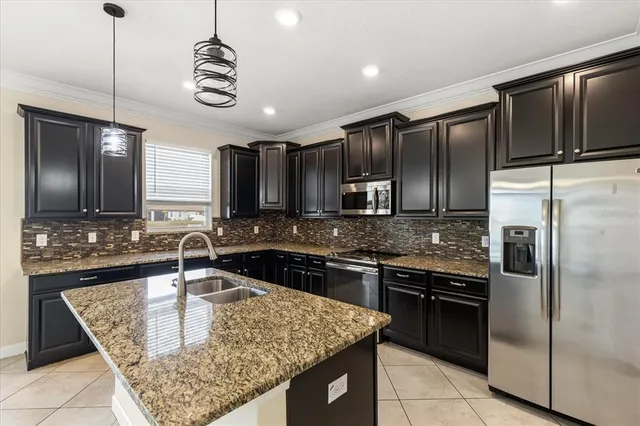 a kitchen with kitchen island granite countertop stainless steel appliances a sink stove and refrigerator