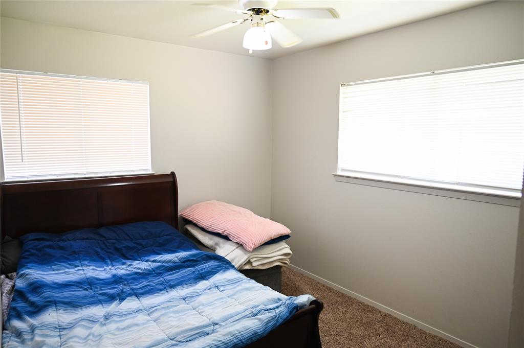 1352 Simpson Drive Hurst, TX 76053 - Photo 14 of 40 Room featuring light neutral wall paint, two windows with blinds, and a ceiling fan with integrated lighting