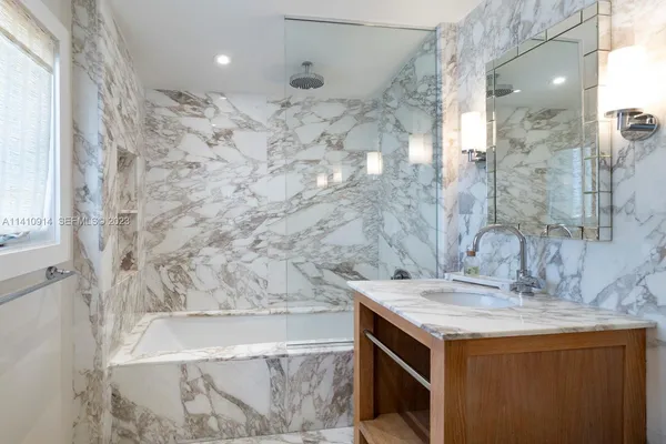 a bathroom with a granite countertop sink a mirror and shower