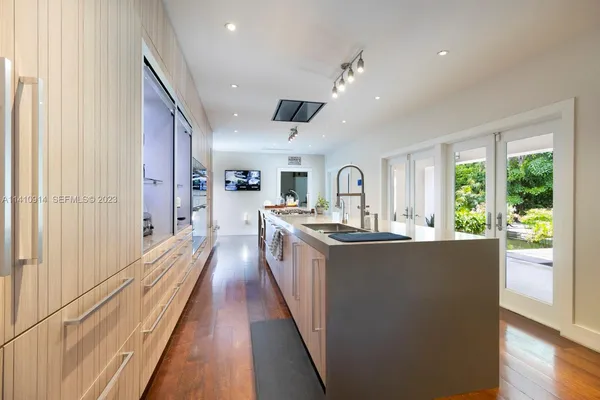 a view of a living room kitchen with a large window a sink and stainless steel appliances