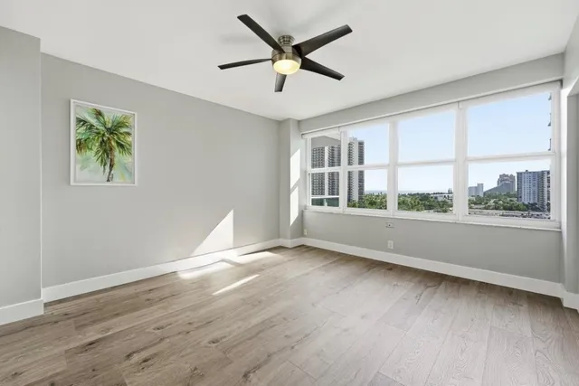 a view of an empty room with a window and wooden floor