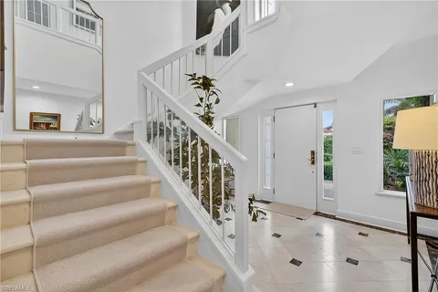 a view of staircase with white walls and a chandelier