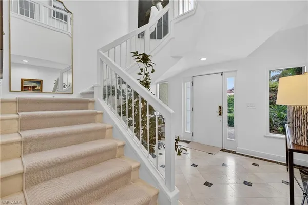 a view of staircase with white walls and a chandelier