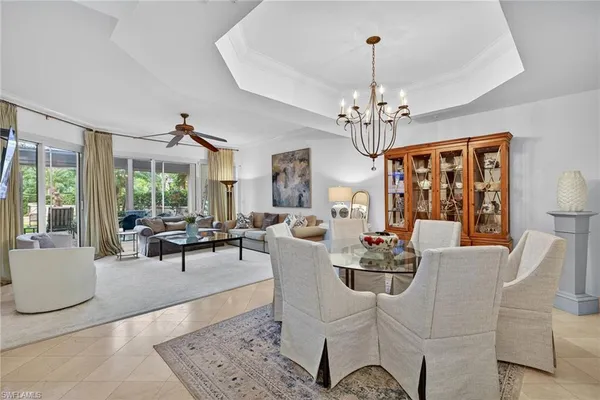 a dining room with wooden floor a chandelier a glass table and chairs