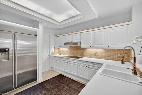 a kitchen with granite countertop a refrigerator and white cabinets