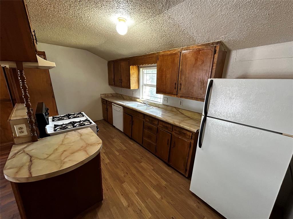 910 West Long Stephenville, TX 76401 - Photo 23 of 40 a kitchen with wooden cabinets a refrigerator and a stove