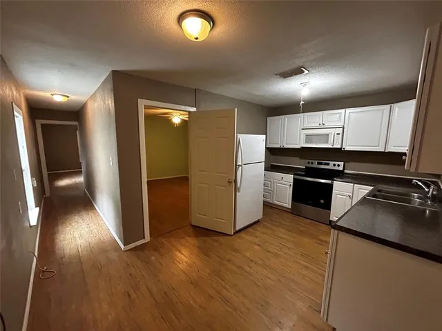 a kitchen with stainless steel appliances granite countertop a refrigerator a sink and wooden floor