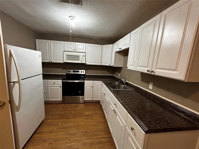 a kitchen with granite countertop stainless steel appliances a refrigerator a sink and cabinets