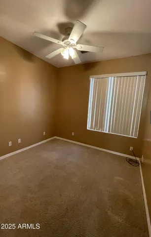 an empty room with a chandelier fan and windows