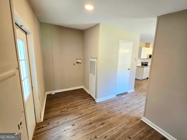a view of an empty room with wooden floor and a bathroom