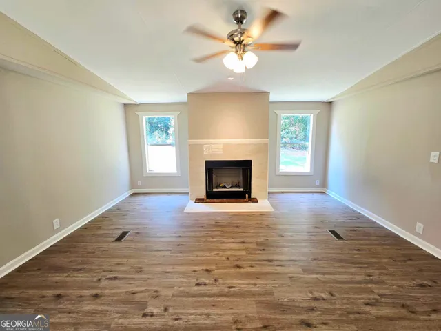 an empty room with windows fireplace and wooden floor