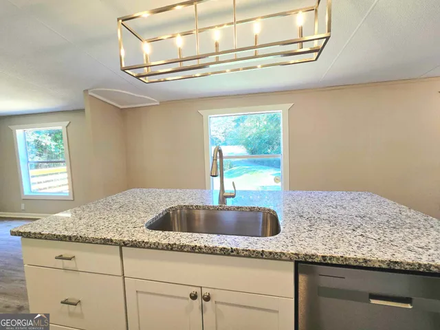 a kitchen with granite countertop a sink and chandelier
