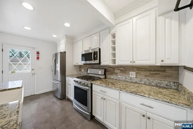 a kitchen with stainless steel appliances granite countertop a stove a sink and a refrigerator