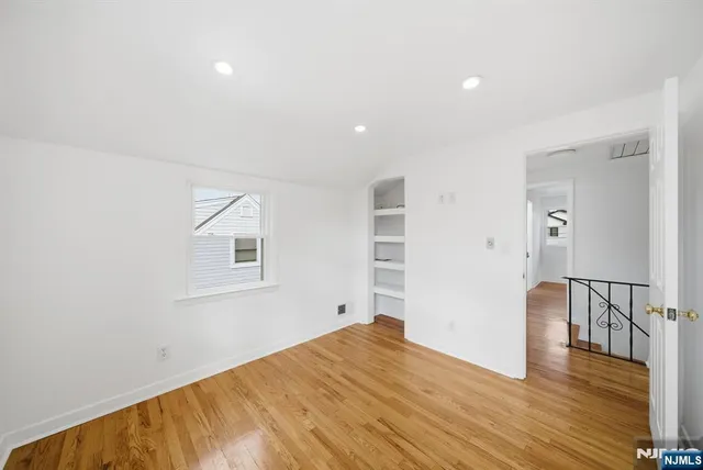 a view of an empty room with wooden floor and closet