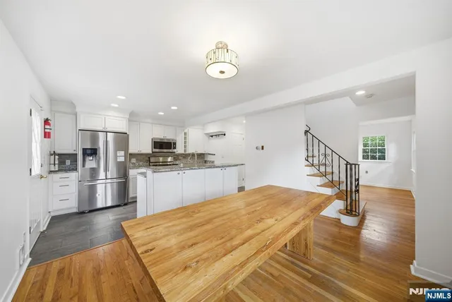 a kitchen with stainless steel appliances kitchen island a refrigerator and a view of living room