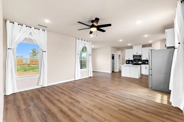 a view of a kitchen with refrigerator and wooden floor