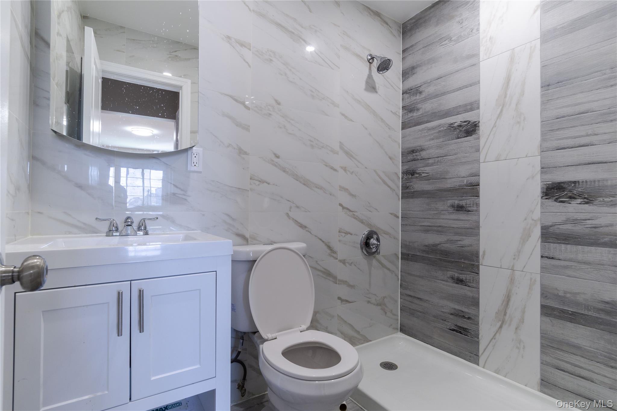 2-15 Beach 96th Street Queens, NY 11693 - Photo 13 of 39 a bathroom with a granite countertop toilet a sink and mirror