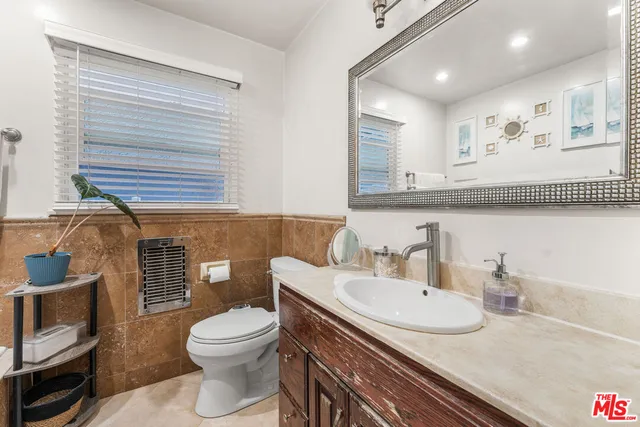 a bathroom with a granite countertop toilet a sink and a mirror