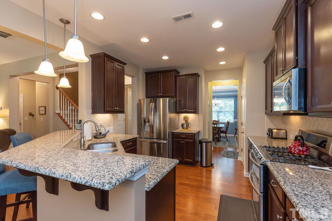 842 Wickham Ridge Road Apex, NC 27539 - Photo 12 of 43 a kitchen with stainless steel appliances granite countertop a kitchen island a stove and a refrigerator