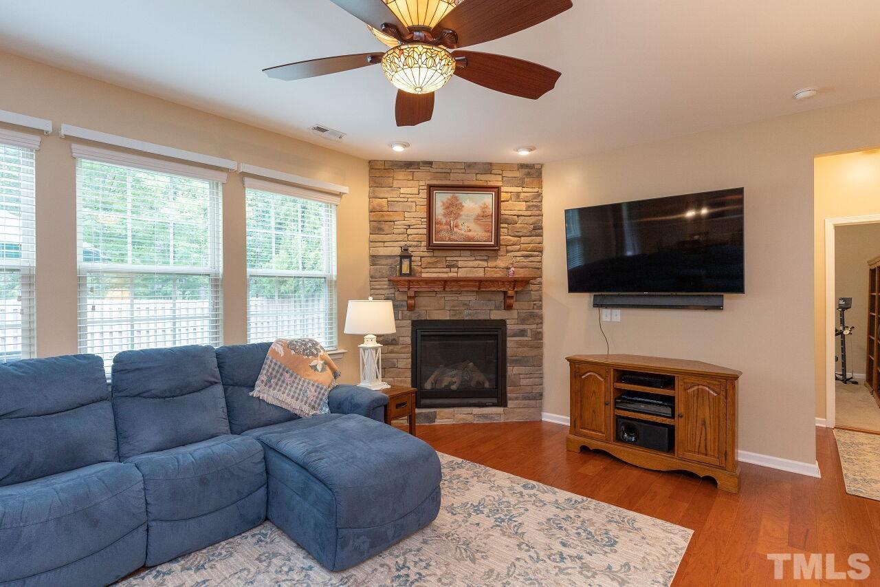 842 Wickham Ridge Road Apex, NC 27539 - Photo 15 of 43 a living room with furniture a fireplace and a flat screen tv