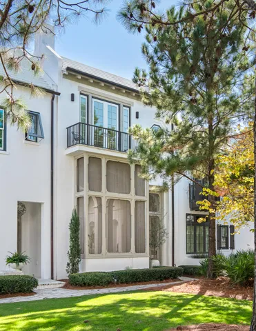 a front view of a building with a garden and trees