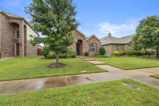a view of house in front of a big yard with large trees