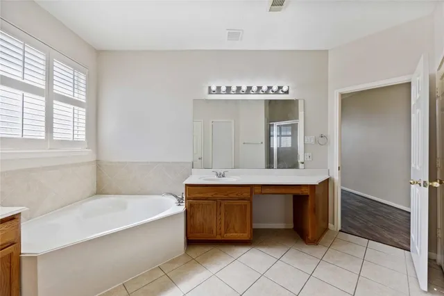 a spacious bathroom with a tub sink and mirror