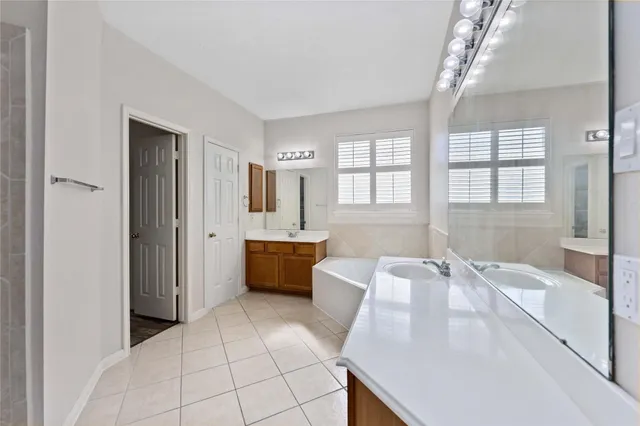 a spacious bathroom with a tub sink shower and mirror