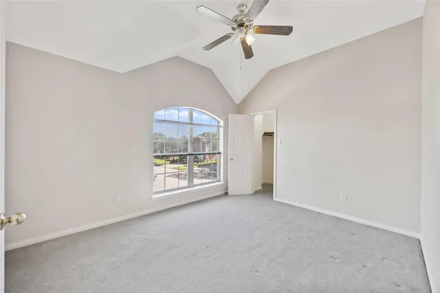 an empty room with chandelier fan and windows