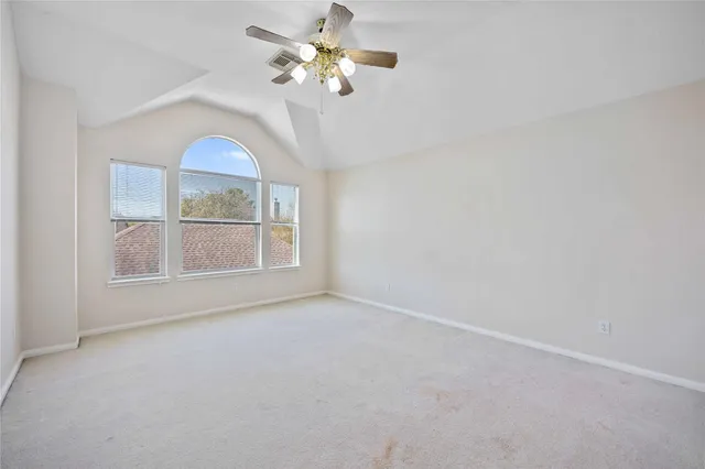 an empty room with chandelier fan and windows