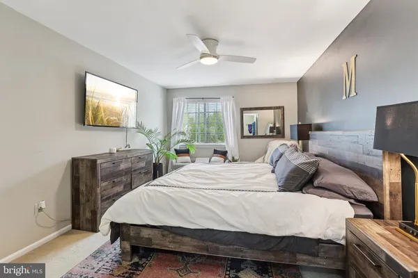 a bedroom with a bed a dresser and potted plant with the wooden floor