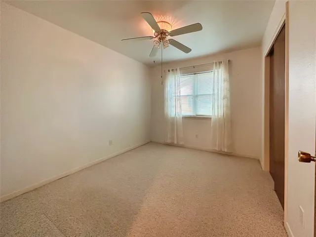 an empty room with a window and a chandelier fan