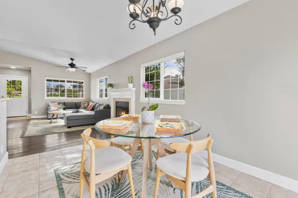 a dining room with wooden floor a chandelier a wooden table and chairs