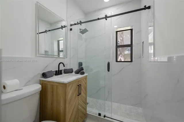 a bathroom with a granite countertop sink a toilet and shower