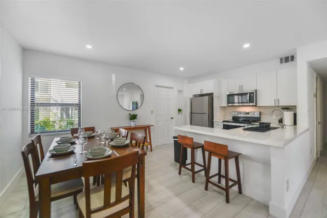 a kitchen with stainless steel appliances a table chairs refrigerator and a sink