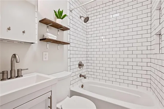 a bathroom with a bathtub shower sink vanity and toilet