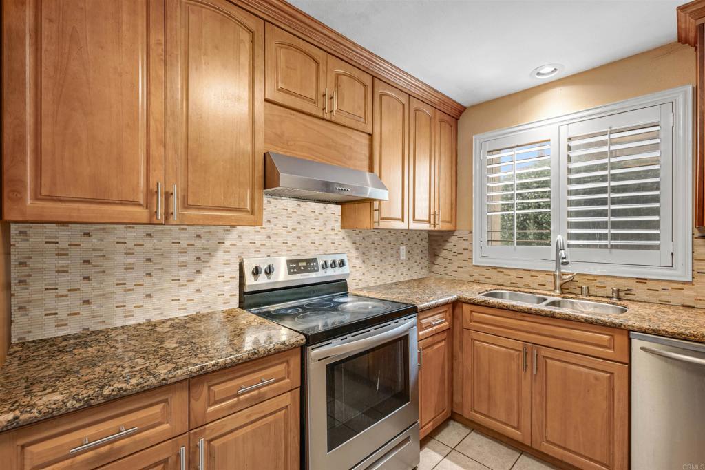 a kitchen with granite countertop stainless steel appliances white cabinets sink and window