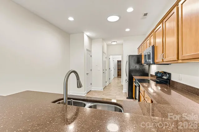 a kitchen with stainless steel appliances granite countertop a sink a stove and a refrigerator