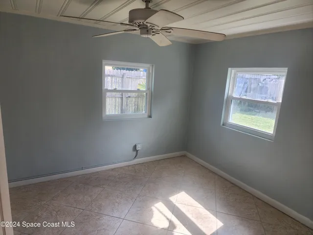 an empty room with windows and fan