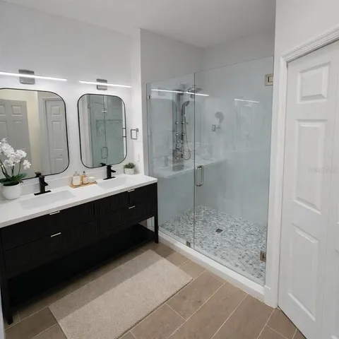 a bathroom with a double vanity sink mirror and shower