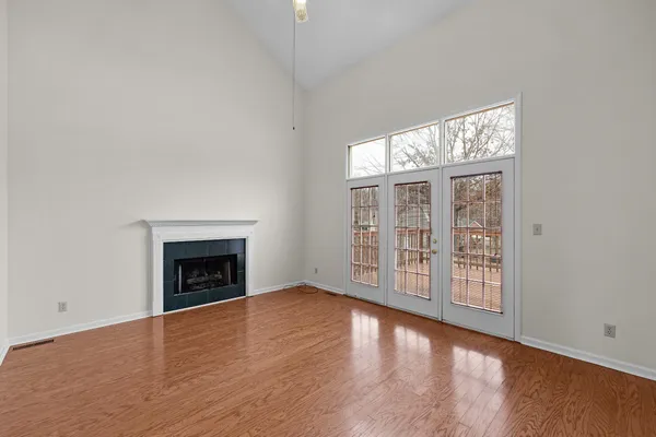 an empty room with wooden floor fireplace and windows