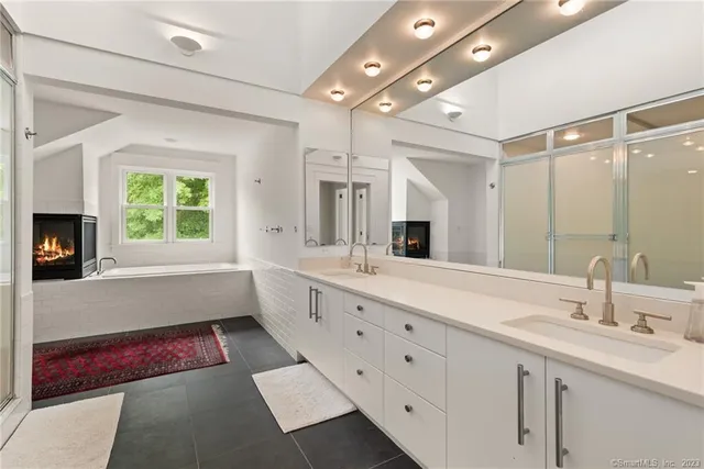 a bathroom with a tub sink double vanity granite and a window