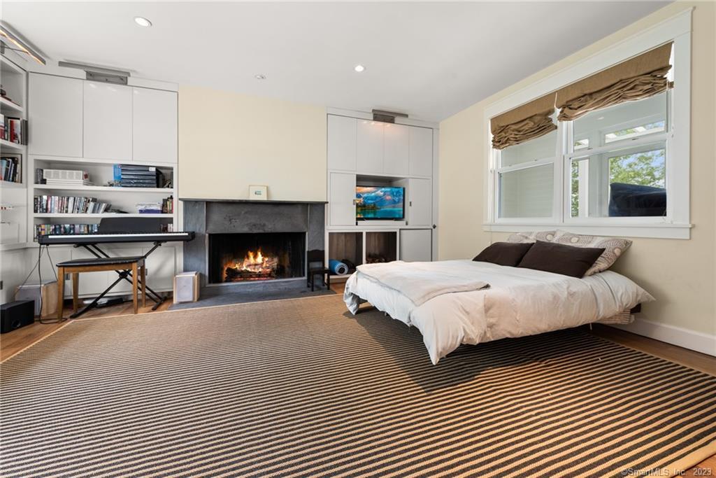 141 Geer Mountain Road South Kent, CT 06785 - Photo 18 of 33 a spacious bedroom with a bed a fireplace and a window
