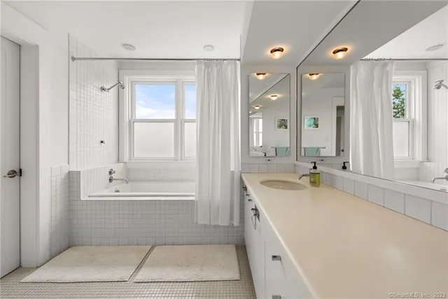 a bathroom with a tub a sink and mirror