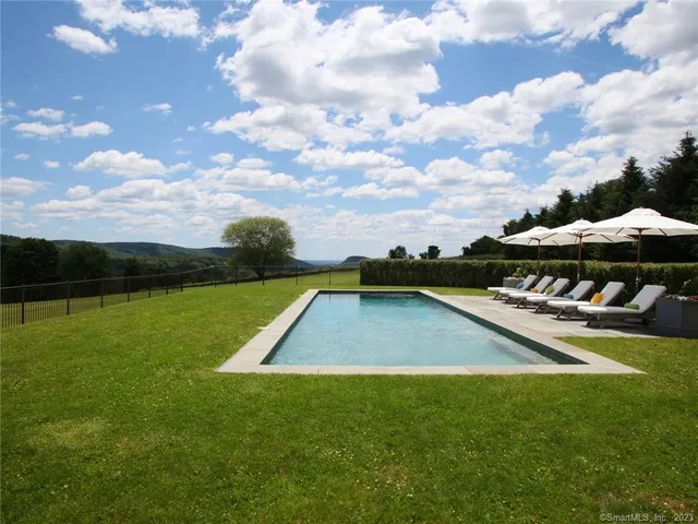 a view of swimming pool with seating area and trees in the background