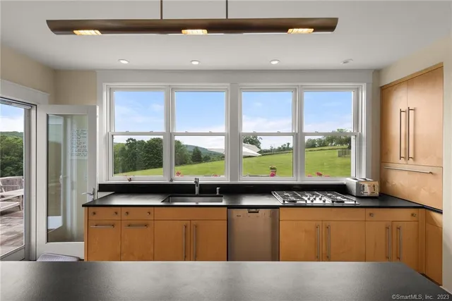 a kitchen with stainless steel appliances granite countertop a stove a sink and a large window