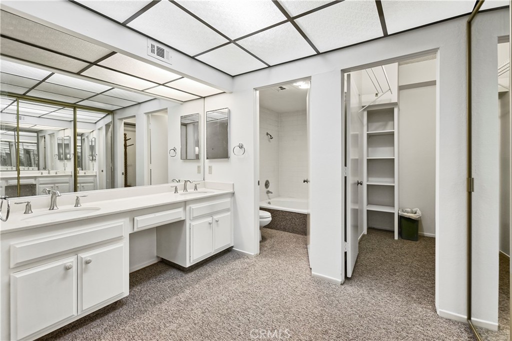 5555 Canyon Crest Drive, Unit 1F Riverside, CA 92507 - Photo 9 of 27 a large white bathroom with a double vanity sink a toilet and a tub