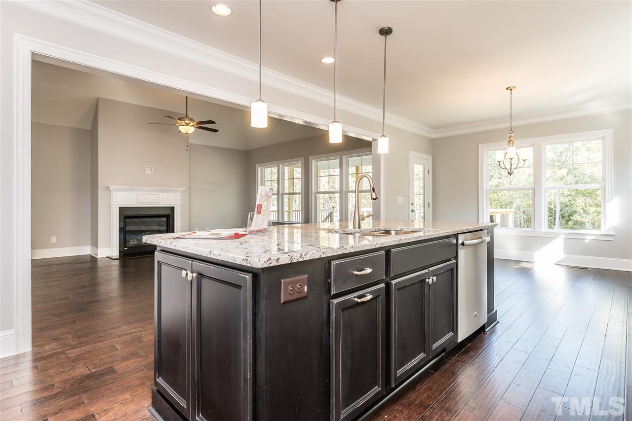 1121 Harrison Ridge Road Wake Forest, NC 27587 - Photo 8 of 25 a kitchen with kitchen island granite countertop a stove a sink and wooden floor